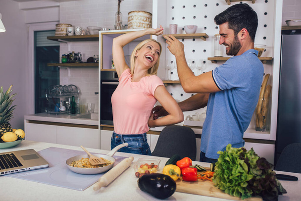 Junges Paar lächelt beim Kochen von gesundem Essen in der heimischen Küche. - Foto, Bild