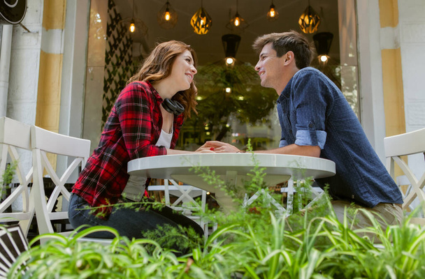 Young couple in love spend time together while sitting at table in outdoor cafe - Foto, Imagem