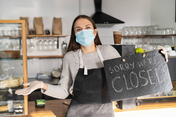 A waitress in a medical mask with closed sign - Fotoğraf, Görsel