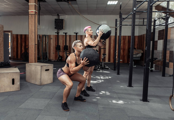 筋肉運動の女性は、現代のジムで医療ボールを訓練します。クロスフィット、機能トレーニング - 写真・画像