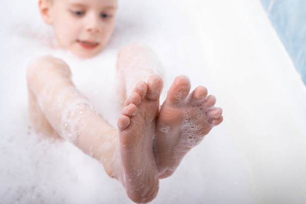 Child's foot in soapy foam. Taking a bath, hygiene procedures. - Photo, image