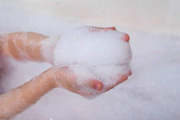 Children's hands hold the foam. Taking a bath, hygiene procedures. - Foto, imagen