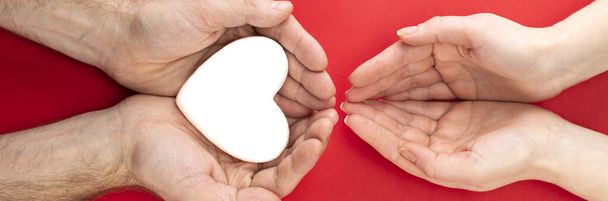 ανδρικά και γυναικεία χέρια με λευκή καρδιά, υγειονομική περίθαλψη, αγάπη και οικογενειακή ασφάλιση έννοια, παγκόσμια ημέρα της καρδιάς, παγκόσμια ημέρα υγείας, ανάδοχη οικογένεια, διεθνής ημέρα της οικογένειας. - Φωτογραφία, εικόνα