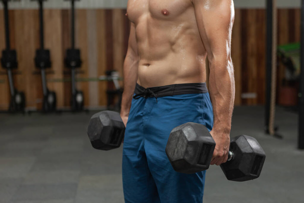 Uomo muscolare che tiene i manubri pesanti in palestra - Foto, immagini