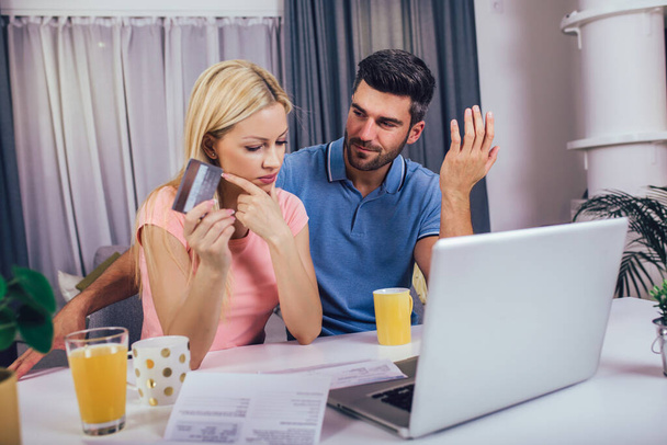 Couple at home paying bills with laptop and credit card - Foto, Bild