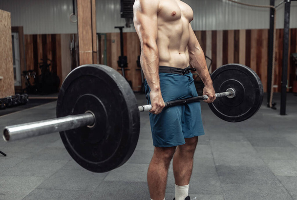 Uomo bodybuilding muscolare facendo esercizio stacco con un bilanciere pesante in un moderno centro benessere. Culturismo e Fitness - Foto, immagini