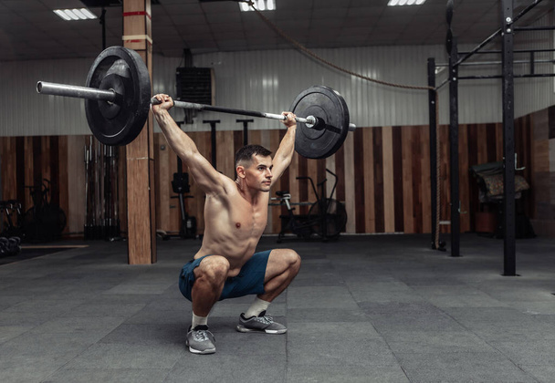 Μυώδης άνθρωπος εξάσκηση βαρύ βαρίδι γενικά στο σύγχρονο γυμναστήριο. Bodybuilding και Γυμναστήριο - Φωτογραφία, εικόνα