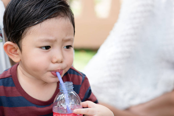 Muotokuva Aasian pieni poika, kun vesi juominen jälkeen pelaa puistossa leikkikentällä lapsille ja lapsille. Terveys lapsille. - Valokuva, kuva