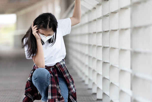 Zmęczony azjatycki nastolatek ma ciężkie objawy bólu głowy i wyczerpanie w miejscach publicznych, objawy rozprzestrzeniania się koronawirusu, Covid19 - Zdjęcie, obraz