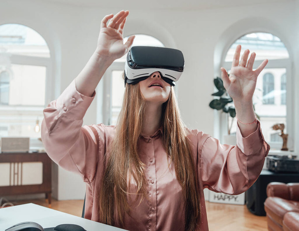 Amazed woman enjoys virtual reality headset in office room - Zdjęcie, obraz