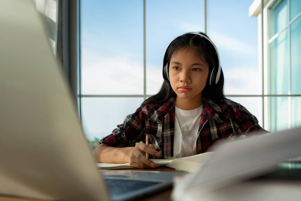 Női hallgató visel fejhallgatót, és keres laptop számítógépes tanulmány online hallgatni nézni tanár otthon tanul az online e-learning rendszer képzés során. Távolsági oktatás koncepciója. - Fotó, kép