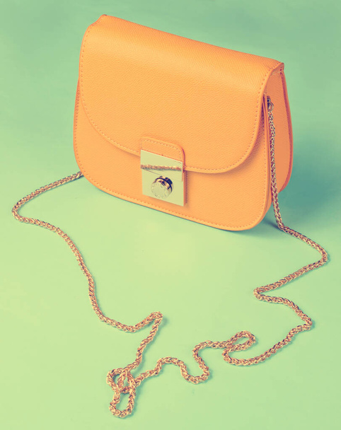 Mini bolso de cuero amarillo con cadena sobre fondo amarillo. - Foto, imagen
