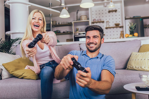 Hermosa pareja joven jugando videojuegos en casa. - Foto, Imagen