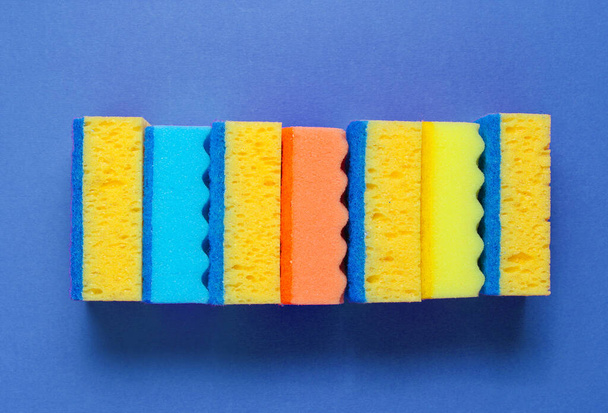 Stack of colored cleaning sponges isolated on blue background. - Foto, afbeelding