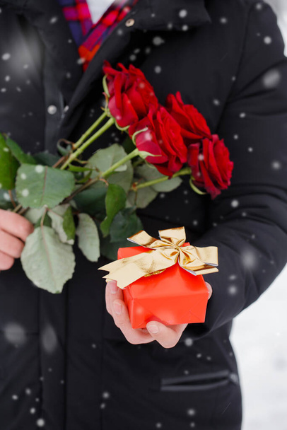 Красивый романтичный молодой человек с букетом красных роз в руках - Фото, изображение