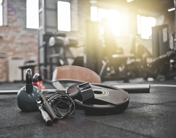 Разобранная штанга, медицинский мяч, гири, гантель, скакалка, лежащая на полу в спортзале. Спортивный инвентарь для тренировок с бесплатным весом. Функциональное обучение - Фото, изображение