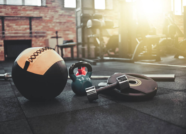 Сборная штанга, медицинский мяч, гири, гантели лежат на полу в спортзале. Спортивный инвентарь для тренировок с бесплатным весом. Функциональное обучение - Фото, изображение