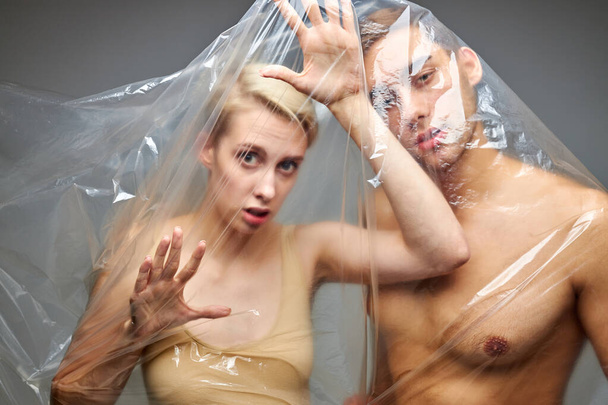 portrait of hopelessness couple wrapped with disposable plastic bags - Fotó, kép