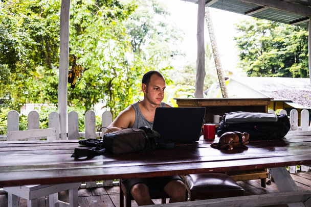 Digitális nomád férfi dolgozik egy faházban a dzsungelben - Fotó, kép
