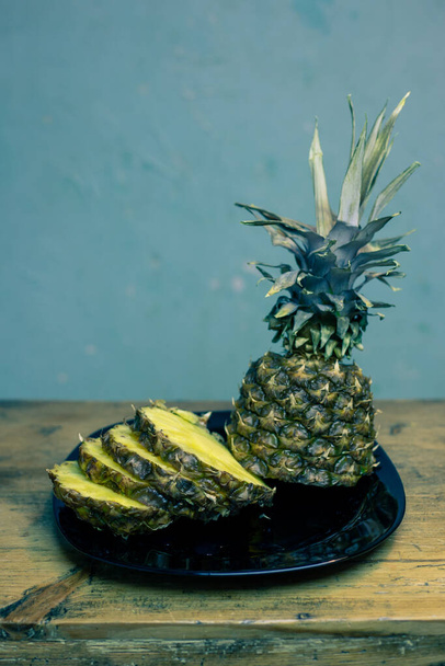 Pineapple on a plate. Cut and on a wooden table. - Фото, зображення
