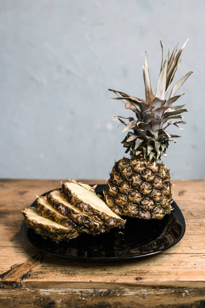 Pineapple on a plate. Cut and on a wooden table. - Valokuva, kuva