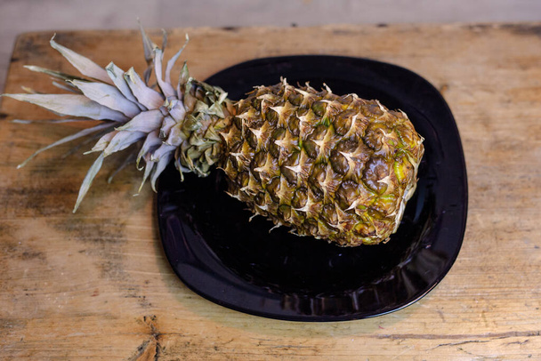 Pineapple on the kitchen table in a plate - Φωτογραφία, εικόνα