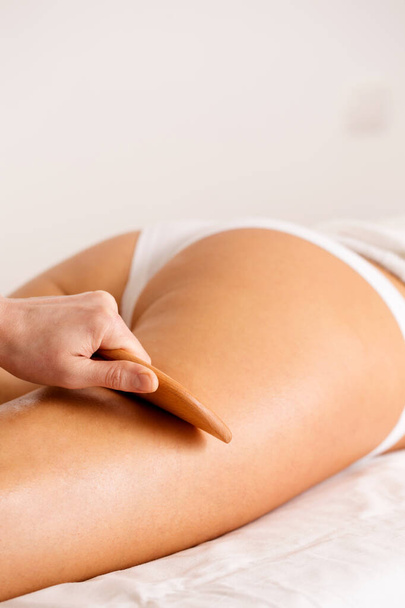 Massage therapist doing anti-cellulite medical massage. Anti-cellulite massage with wooden tool blade, close up - Photo, Image