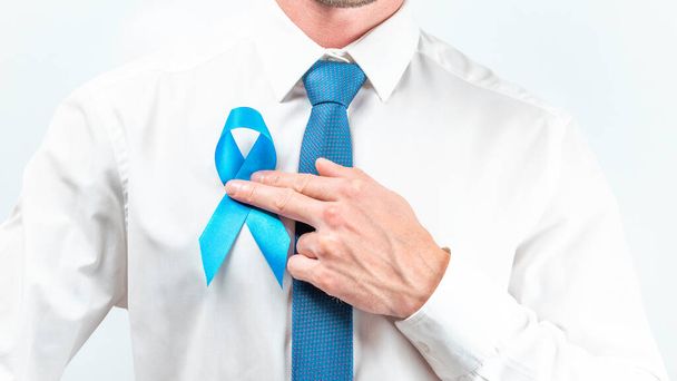 Kankermensen. Hipster mannen in helder shirt, cyaan stropdas met blauw lint in handen op witte achtergrond. Bewustmaking prostaatkanker van de gezondheid van mannen in november. Het concept van de gezondheidszorg en de wereldkankerdag - Foto, afbeelding