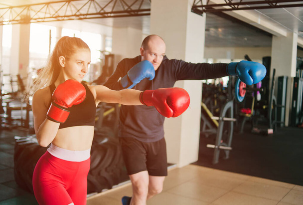 Couple exercising punching. Young woman and man training punches in boxing gloves at the gym. - Photo, Image