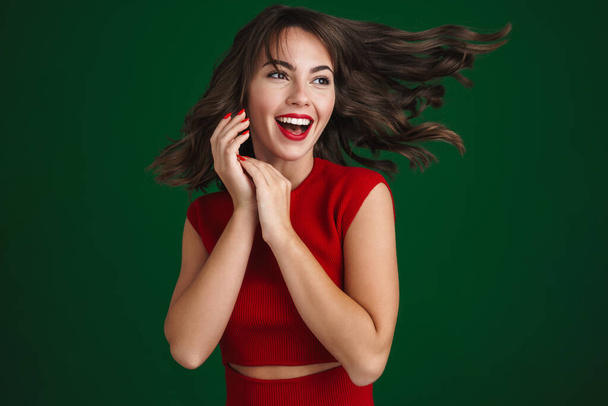 Beautiful happy brunette girl laughing and looking aside isolated over green background - Foto, afbeelding