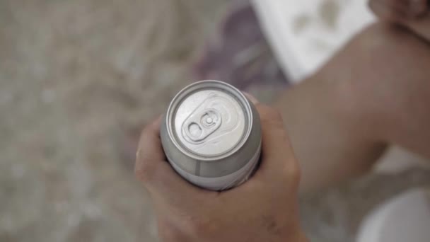 Mano masculina con una lata de cerveza fría, de cerca. El hombre abre una lata de aluminio de bebida alcohólica. - Metraje, vídeo