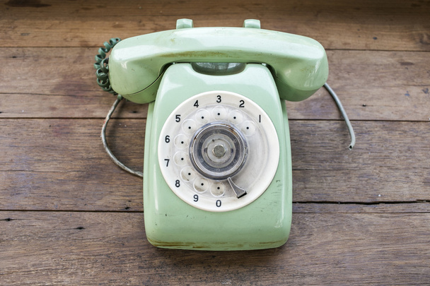 groene vintage telefoon op bruin houten bureau achtergrond - Foto, afbeelding