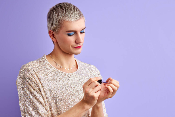 concentrated man with make-up applies nail polish - Fotoğraf, Görsel