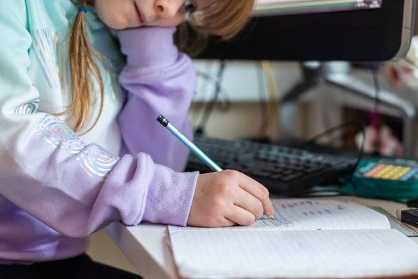 Niña trabajando en casa durante el encierro como los niños necesitan a la escuela en casa a través de aprendizaje en línea - Foto, Imagen