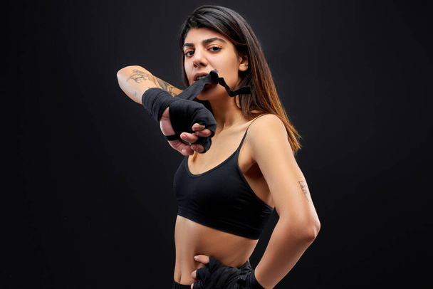 muscular strong female puts on gloves for boxing - Valokuva, kuva