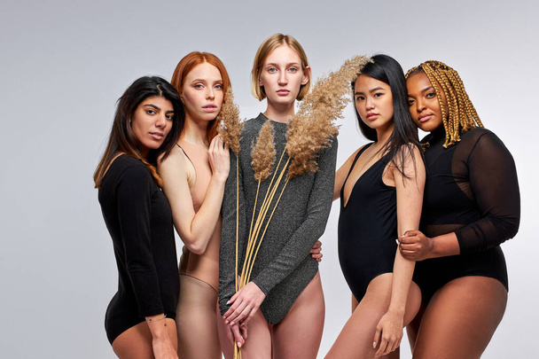 portrait of young beautiful diverse models in bodysuits posing at camera - Foto, Imagen