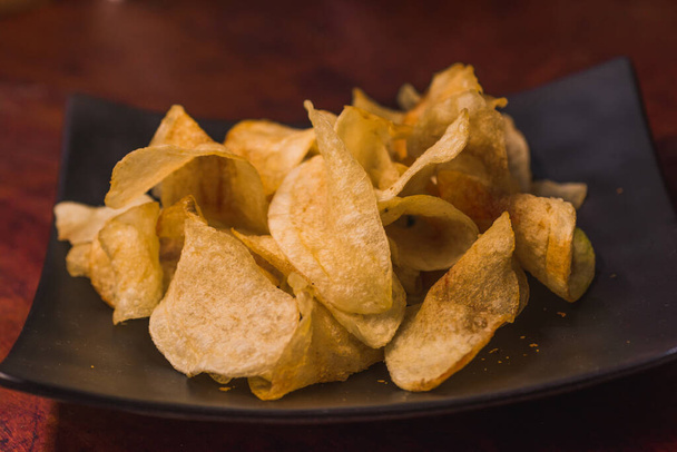 Chips served on a black plate on a wooden table, traditional Mexican snack 2 - Foto, Imagen