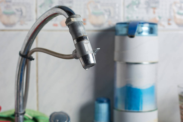 Sluitingen van moderne waterzuiveraar geïnstalleerd op waterkraan in de keuken van een huis. - Foto, afbeelding