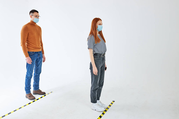 two young people in protective medical face masks keep distance, protection from coronavirus - 写真・画像