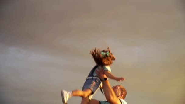 Отец подбрасывает свою маленькую дочь в воздух со счастливым лицом на ржаное поле. - Кадры, видео