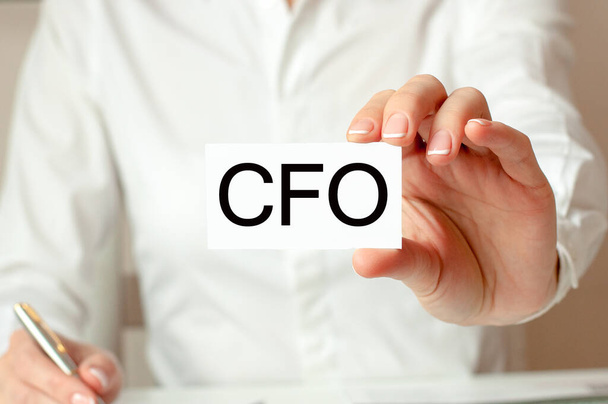 Motiverende woorden: CFO. Een vrouw in een wit shirt draagt een stuk papier met de tekst: CFO. Bedrijfsconcept voor bedrijven. CFO - afkorting van Chief Financial Officer. - Foto, afbeelding