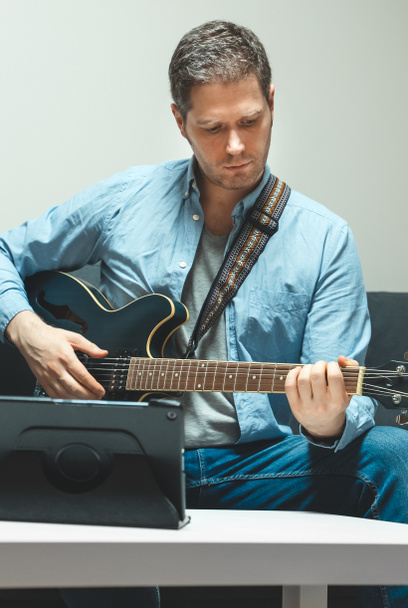 De mens leert gitaar spelen. Online les op afstand. - Foto, afbeelding