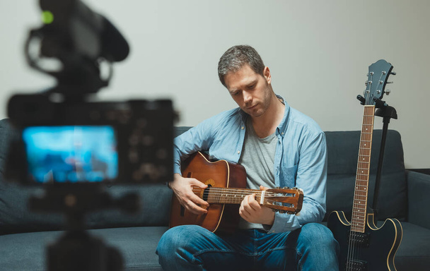 Homme avec guitare espagnole devant la caméra vidéo. - Photo, image