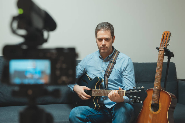 Muž s poloakustickou kytarou před videokamerou. - Fotografie, Obrázek