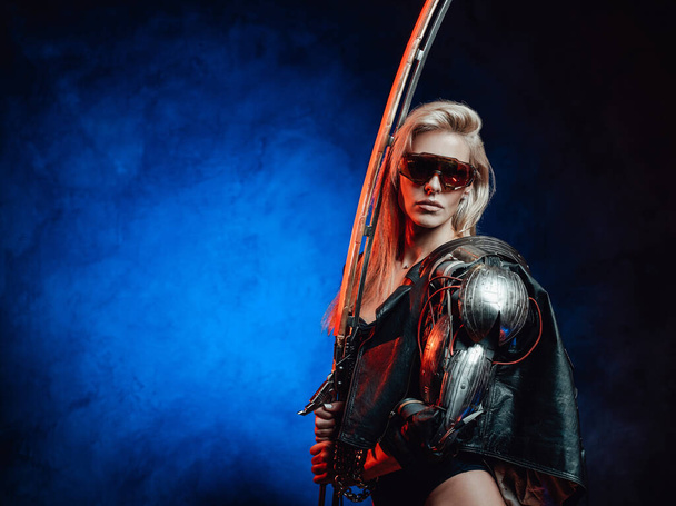 浅黒い背景のサングラスと剣を持つ誘惑的な女性 - 写真・画像