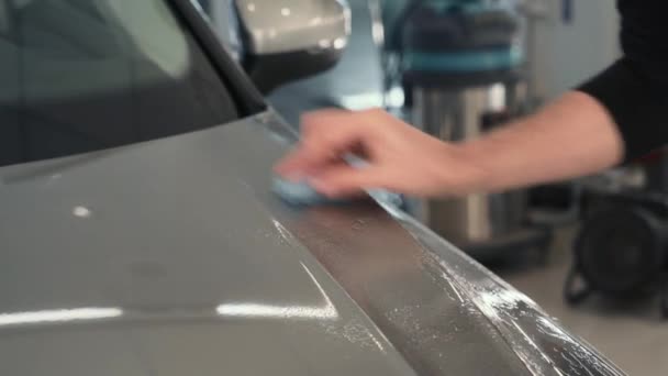 Pracovník ruční čištění karoserie s modrým jílem pro čištění před nanesením ochranné vrstvy nebo nátěru na auto. Detailní koncepce auta - Záběry, video