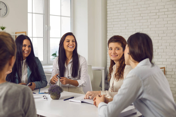 Groep van gelukkige zakenvrouwen ontmoeten elkaar in functie, bespreken grappige ideeën en lachen - Foto, afbeelding