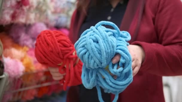 Les mains des femmes choisissent le fil de chenille pour le tissage et le tricot - Séquence, vidéo