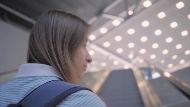 Молодая женщина движется на эскалаторе и смотрит вокруг - замедленная съемка - Кадры, видео