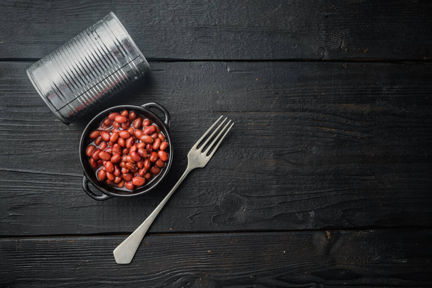 Kırmızı fasulye konservesi, siyah ahşap masa arkaplanı, üst görünüm düz metin için kopyalama alanı ile yatıyordu - Fotoğraf, Görsel